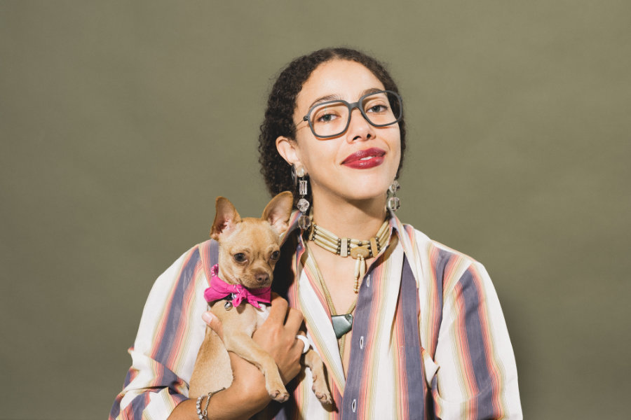 Junge Frau mit moderner ausdrucksstarker Brille und einem Hund auf dem Arm